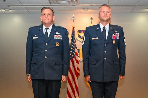 Two men stand at attention at a ceremony.