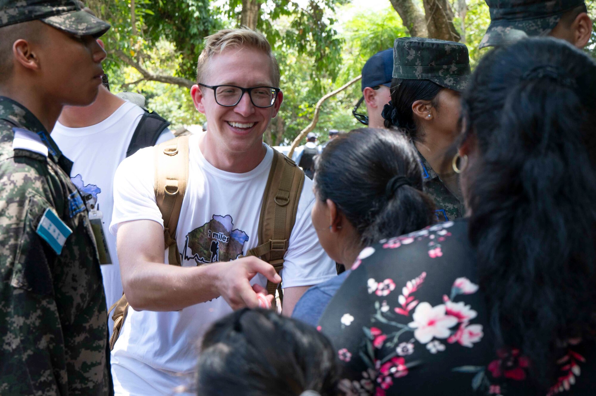A person smiling while they hand off a bag to a woman.