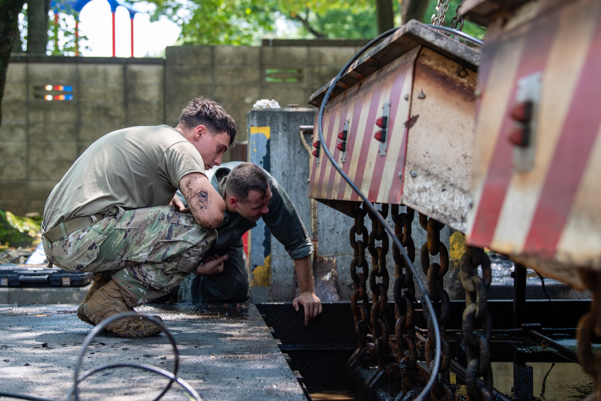 U.S. Air Force Senior Airman Branson Sutherland, 374th Civil Engineer Squadron power production journeyman, and Master Sgt. Zachary Bieranowski, 374th CES power production NCO in charge, inspect an active vehicle barrier system prior to routine maintenance at Yokota Air Base, Japan.