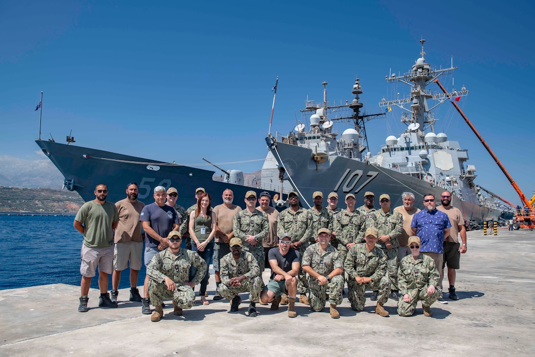 Sailors and civilians from Naval Support Activity (NSA) Souda Bay Port Operations pose in front of Arleigh Burke-class guided-missile destroyer USS Gravely (DDG 107) and Ticonderoga-class guided-missile cruiser USS Philippine Sea (CG 58), nested alongside one another, while moored at the NATO Marathi Pier Complex in Souda Bay, Greece, during a scheduled port visit on June 28, 2024.