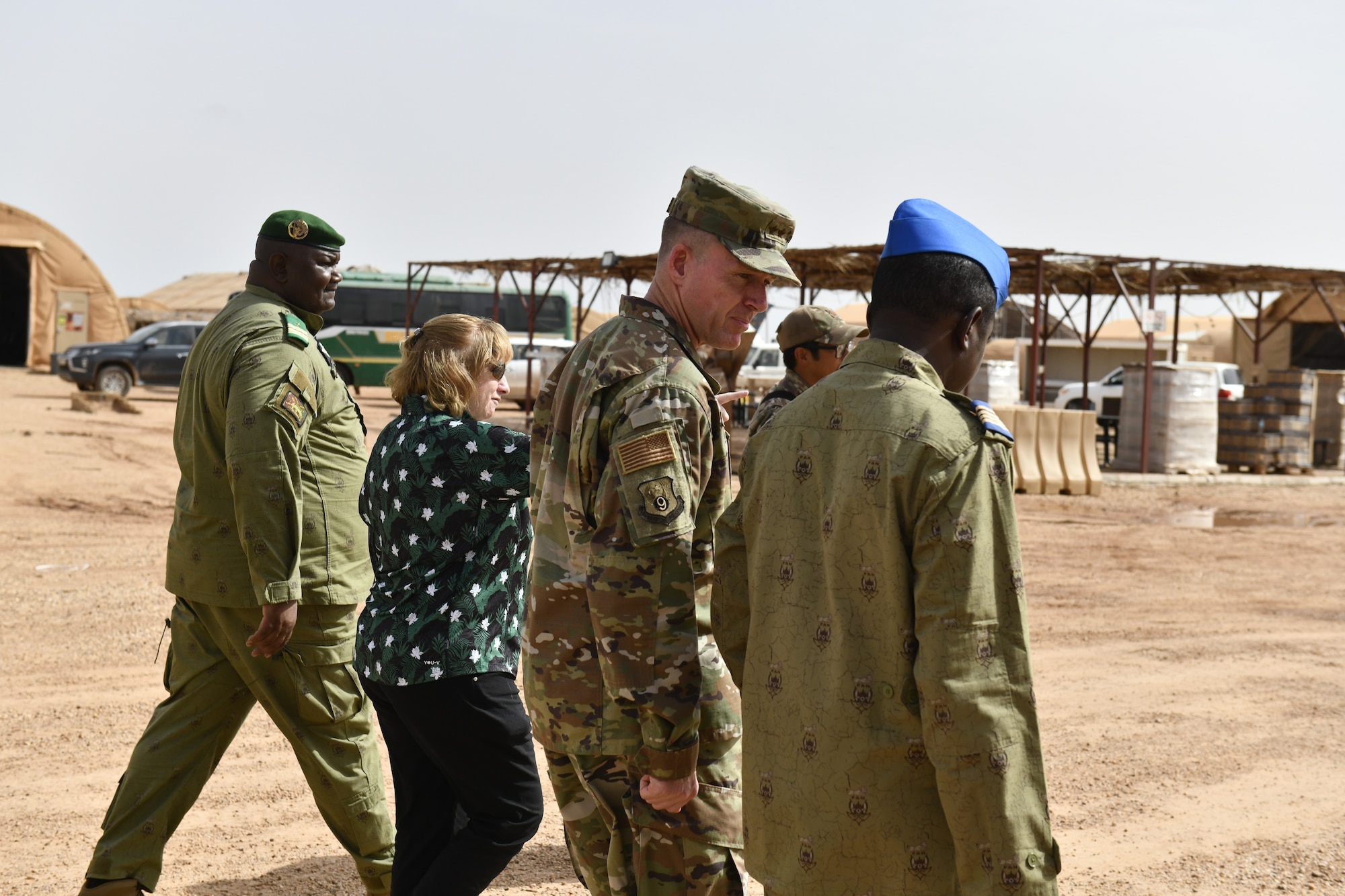 Four people walk and talk in a desert environment