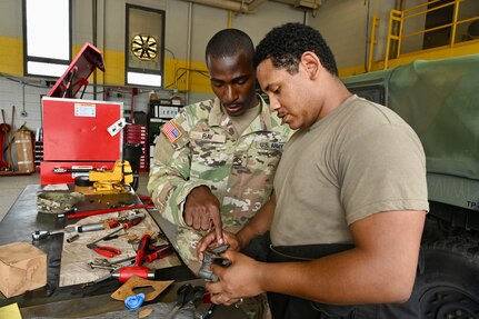 U.S. Army Pfc. James Ray, generator mechanic, and Pfc. Marques Downing, wheeled vehicle mechanic, District of Columbia National Guard, inspect a tactical vehicle part within the Combined Support Maintenance Shop at Joint Base Anacostia-Bolling (JBAB), June 5, 2024. A native of Washington, D.C, Pfc. Ray enlisted in the Army in 2022, motivated by the travel, connections and skills serving in the National Guard provides him.