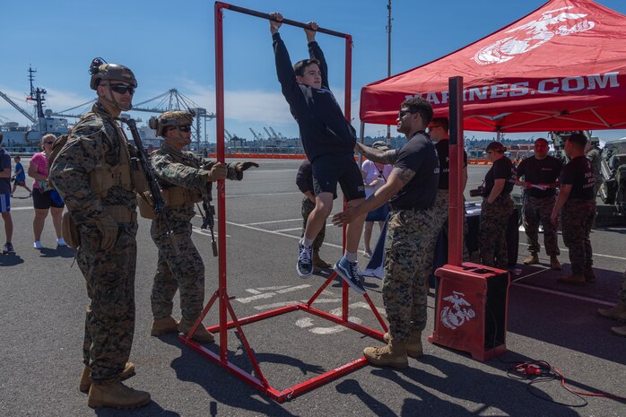 A fleet week attendee participates in a Marine Corps pull-up challenge during Seattle Fleet Week 2024 at Pier 46 in Seattle, Aug. 1, 2024. Seattle Fleet Week is an opportunity for the American public to meet their Navy, Marine Corps and Coast Guard teams and experience America’s sea services. During fleet week, service members participate in various community service events, showcase capabilities and equipment to the community, and enjoy the hospitality of the city and its surrounding areas. (U.S. Marine Corps photo by Cpl. Bruin Largent)
