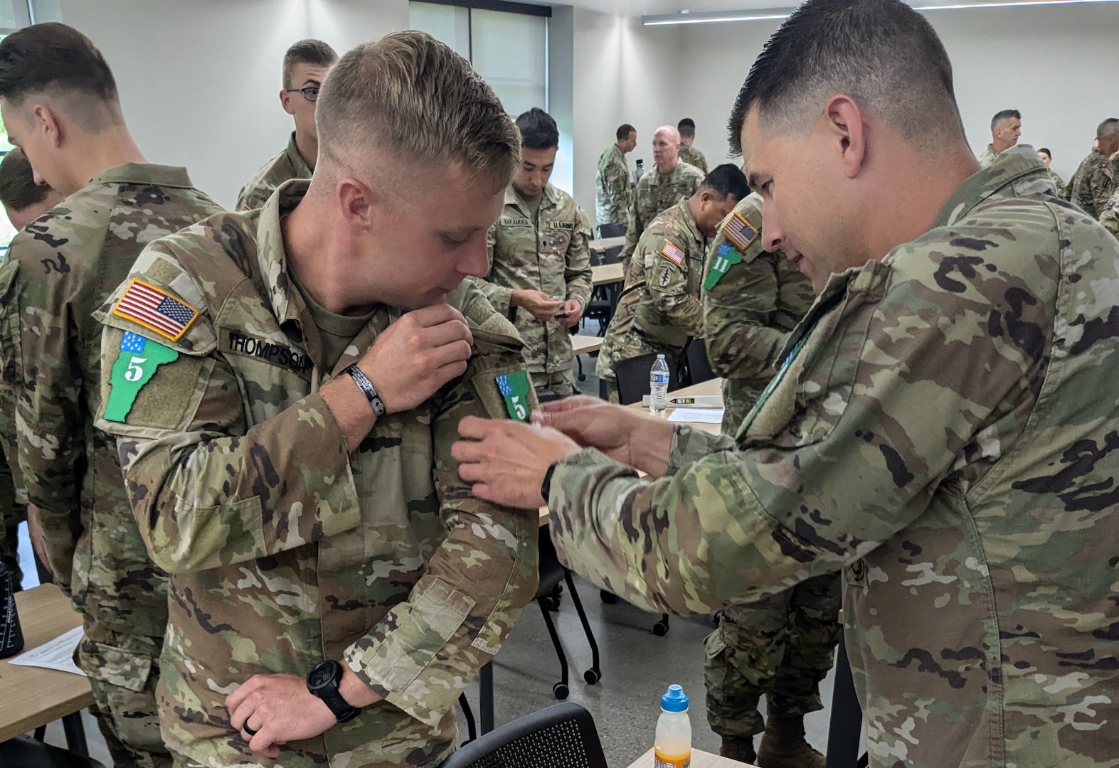 U.S. Army Spc. Trace Thompson, 11B, with the Missouri National Guard receives assistance from U.S. Army Sgt. Chadwick Larter, 79R, with the Massachusetts National Guard, in adjusting his competitor patch after receiving the welcome brief for the Army National Guard Best Warrior finals.