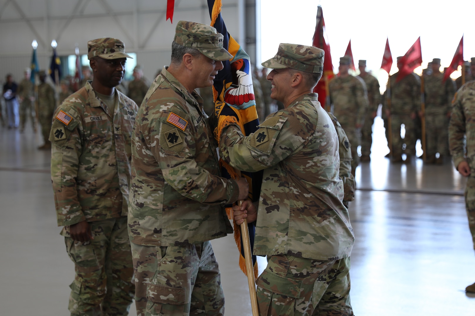 Outgoing commander of 90th Troop Command, Oklahoma National Guard Col. Robert W. Walker, passes the brigade colors to Maj. Gen. Thomas H. Mancino, adjutant general for Oklahoma, at the Army Aviation Support Facility in Lexington, Oklahoma, Aug. 4, 2024.  The ceremony signifies the transfer of command from outgoing commander, Walker, to the incoming commander, Col. Steve D. Cheadle. (Oklahoma National Guard photo by Sgt. Connor McBride)