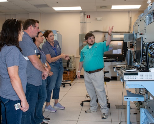 Young male engineer explains equipment to group of teachers.