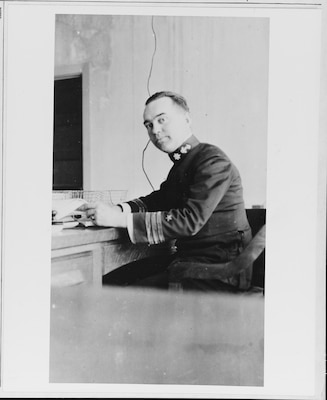 A man in uniform seated at a desk.