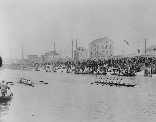 Vessels afloat on a narrow canal with buildings visible in the background.