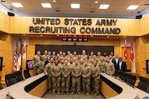 Group of U.S. Army Soldiers and Civilians pose together underneath the U.S. Army Recruiting Command letters