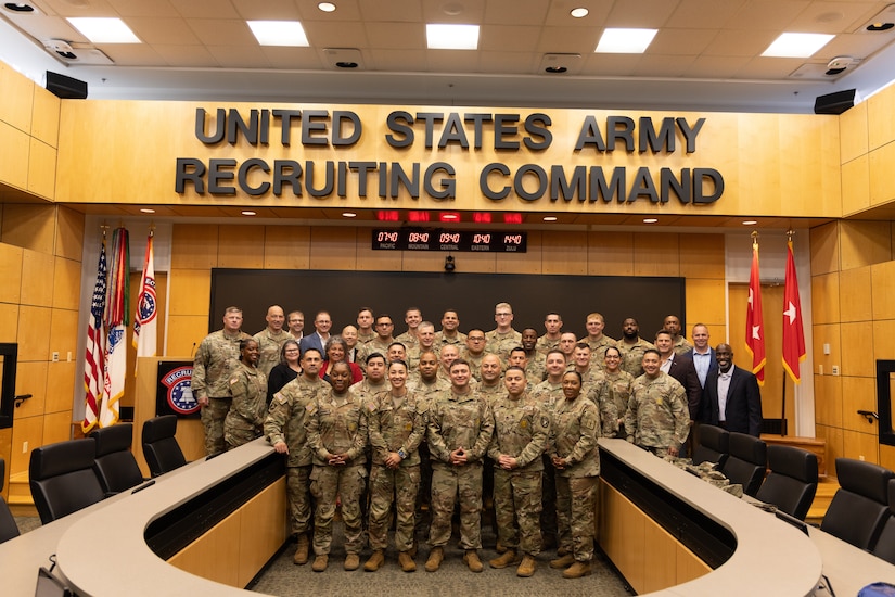 Group of U.S. Army Soldiers and Civilians pose together underneath the U.S. Army Recruiting Command letters