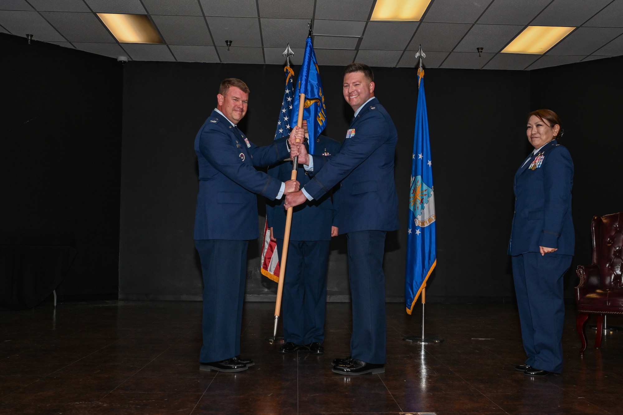 U.S. Air Force Col. Daniel Roberts, 97th Medical Group commander, hands the 97th Healthcare Operations Squadron (HCOS) guidon to Lt. Col. Bradley Howard during a Change of Command ceremony at Altus Air Force Base, Oklahoma, June 14, 2024. The 97th HCOS ensures the 97th Medical Group has the resources, personnel, and systems to provide quality healthcare. (U.S. Air Force photo by Airman Lauren Torres)