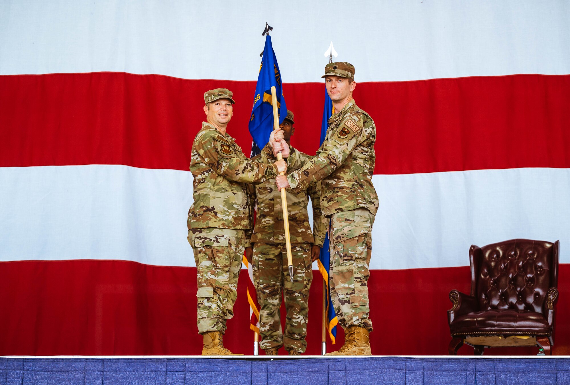 U.S. Air Force Col. Peter Abercrombie (left), 56th Mission Support Group commander, presents Lt. Col. Chris Bahrij (right), incoming 13th Combat Air Base Squadron commander, with the 13th CABS guidon during an assumption of command ceremony, Aug. 5, 2024, at Luke Air Force Base, Arizona.