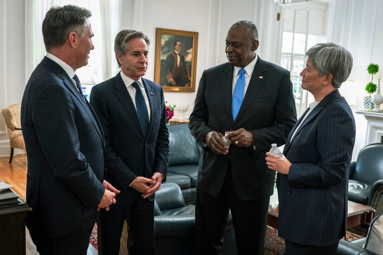 People wearing business attire stand while holding a conversation.