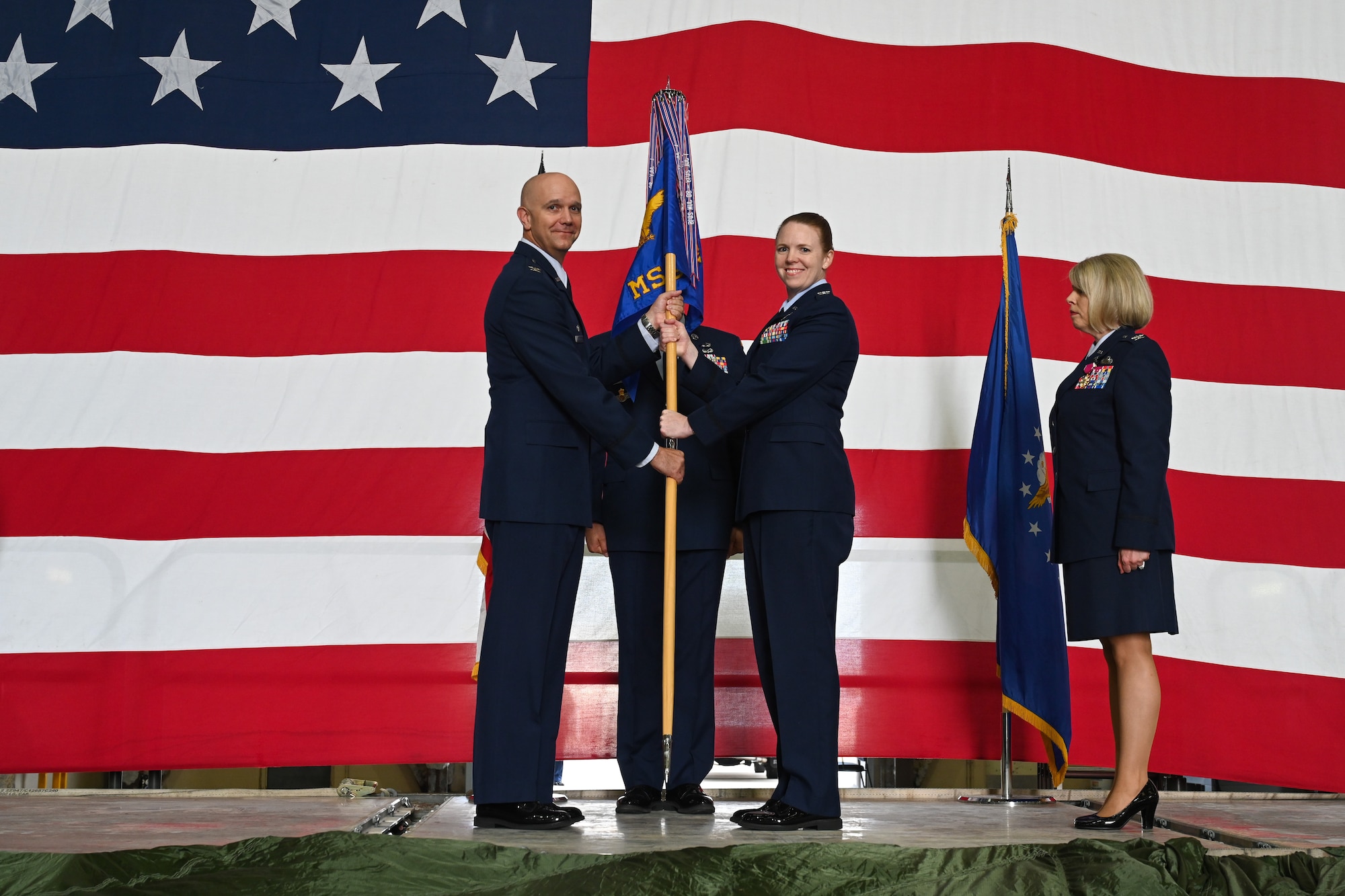 U.S. Air Force Col. Jeffery Marshall, 97th Air Mobility Wing commander, hands the 97th Mission Support Group (MSG) guidon to Col. Amanda Knotts during a Change of Command ceremony at Altus Air Force Base (AFB), Oklahoma, July 26, 2024. The 97th MSG is the largest and most diverse group at Altus AFB, with military and civilian personnel spread across 6 different squadrons. (U.S. Air Force photo by Airman Lauren Torres)