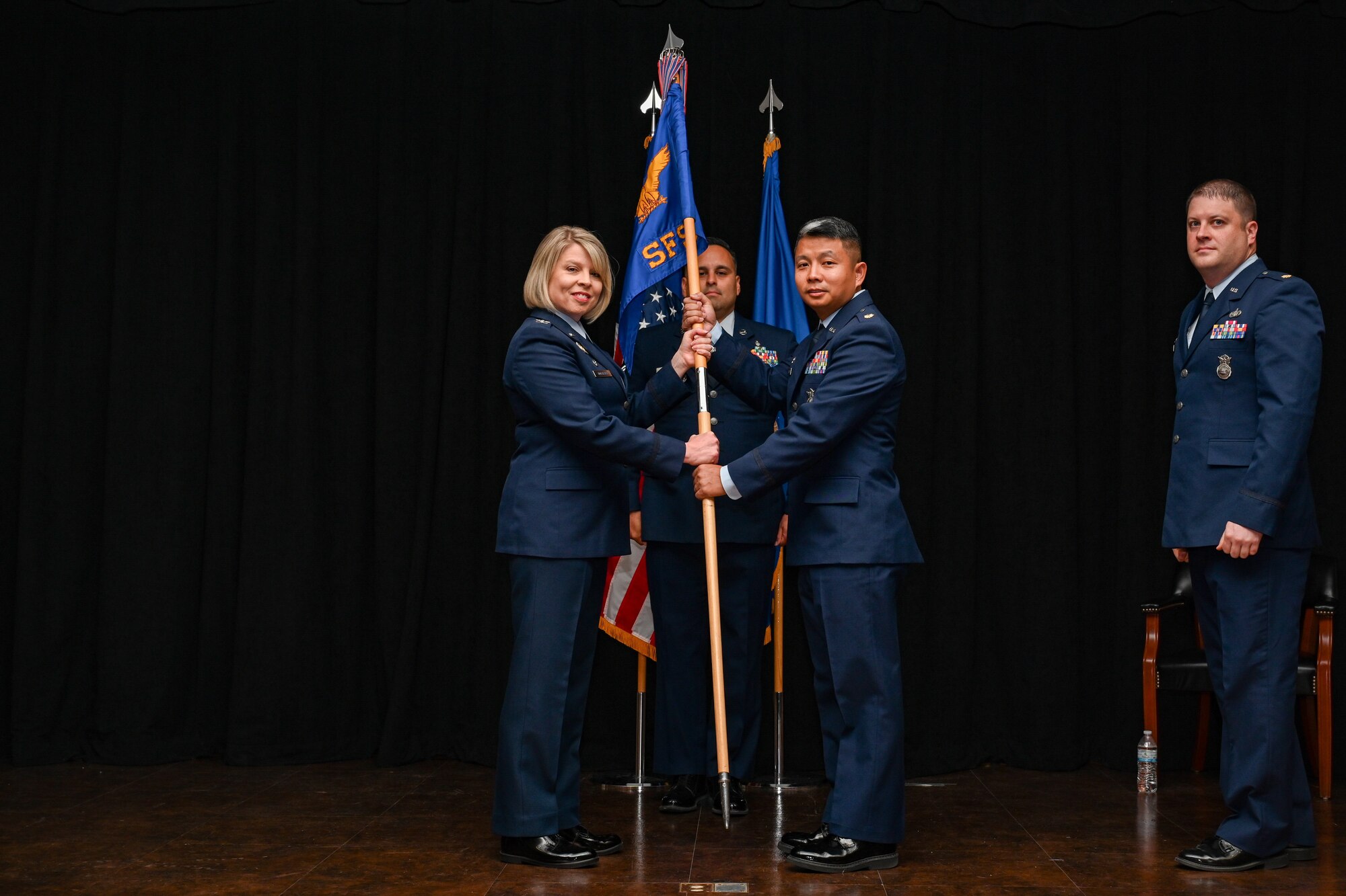 U.S. Air Force Col. Tammy Hollister, 97th Mission Support Group commander, passes the 97th Security Forces Squadron (SFS) guidon to Maj. Chau Tran, 97th SFS commander, during a change of command ceremony at Altus Air Force Base, Oklahoma. The 97th Security Forces Squadron provides security for C-17 Globemaster III, KC-135 Stratotanker, and KC-46 Pegasus aircraft, it also provides force protection and law enforcement support for more than 10,000 active duty military, DOD civilians, contractors, family members and retired personnel in the community. (U.S. Air Force photo by Airman 1st Class Jonah G. Bliss)