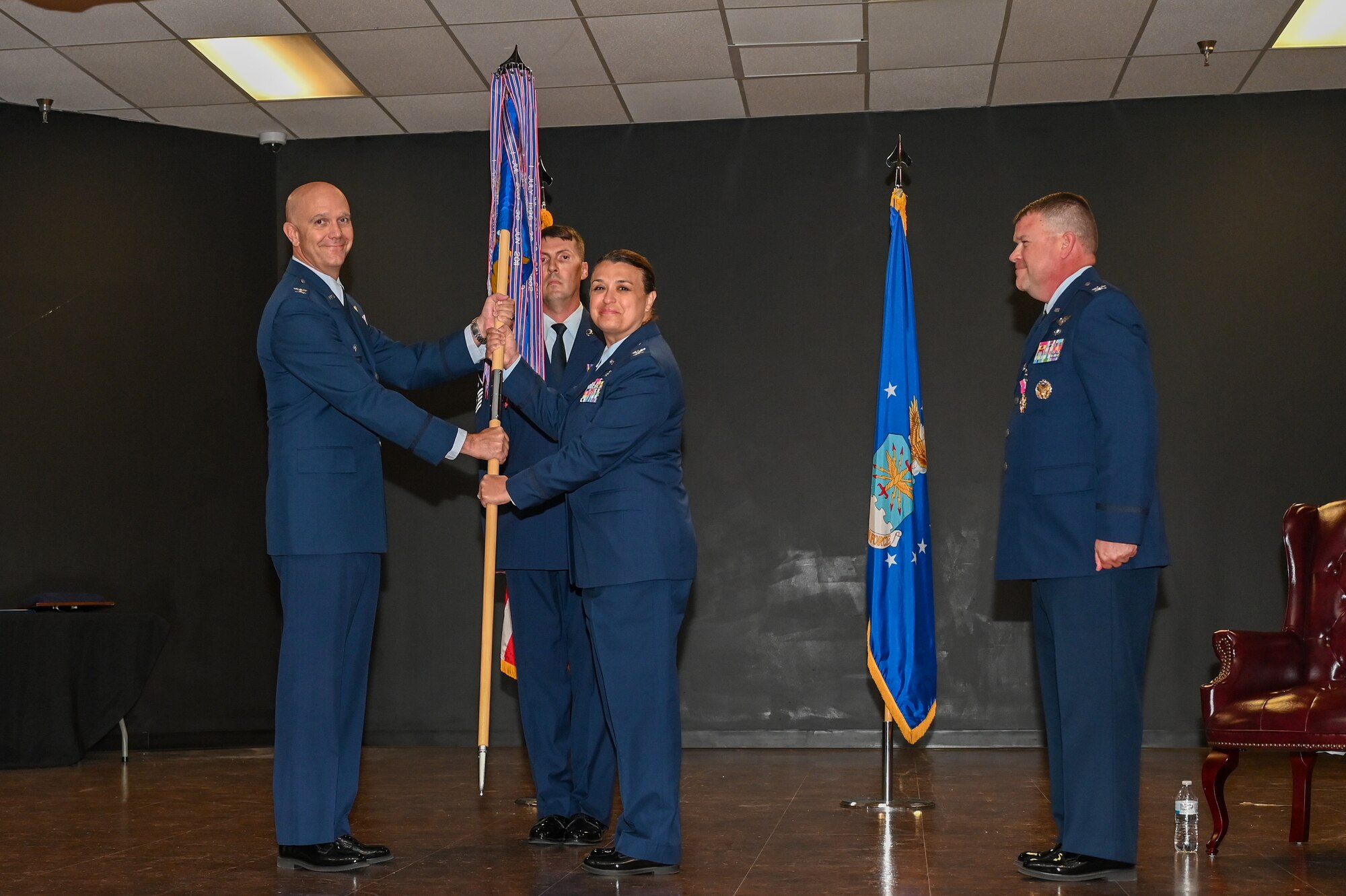 U.S. Air Force Col. Jeff Marshall, 97th Air Mobility Wing commander, passes the 97th Medical Group (MDG) guidon to Col. Claudine Eid, 97th MDG commander, at Altus Air Force Base, Oklahoma, June 28, 2024. The group provides safe and reliable healthcare to 6.4K beneficiaries & 2K aircrew students annually. (U.S. Air Force photo by Senior Airman Kari Degraffenreed)