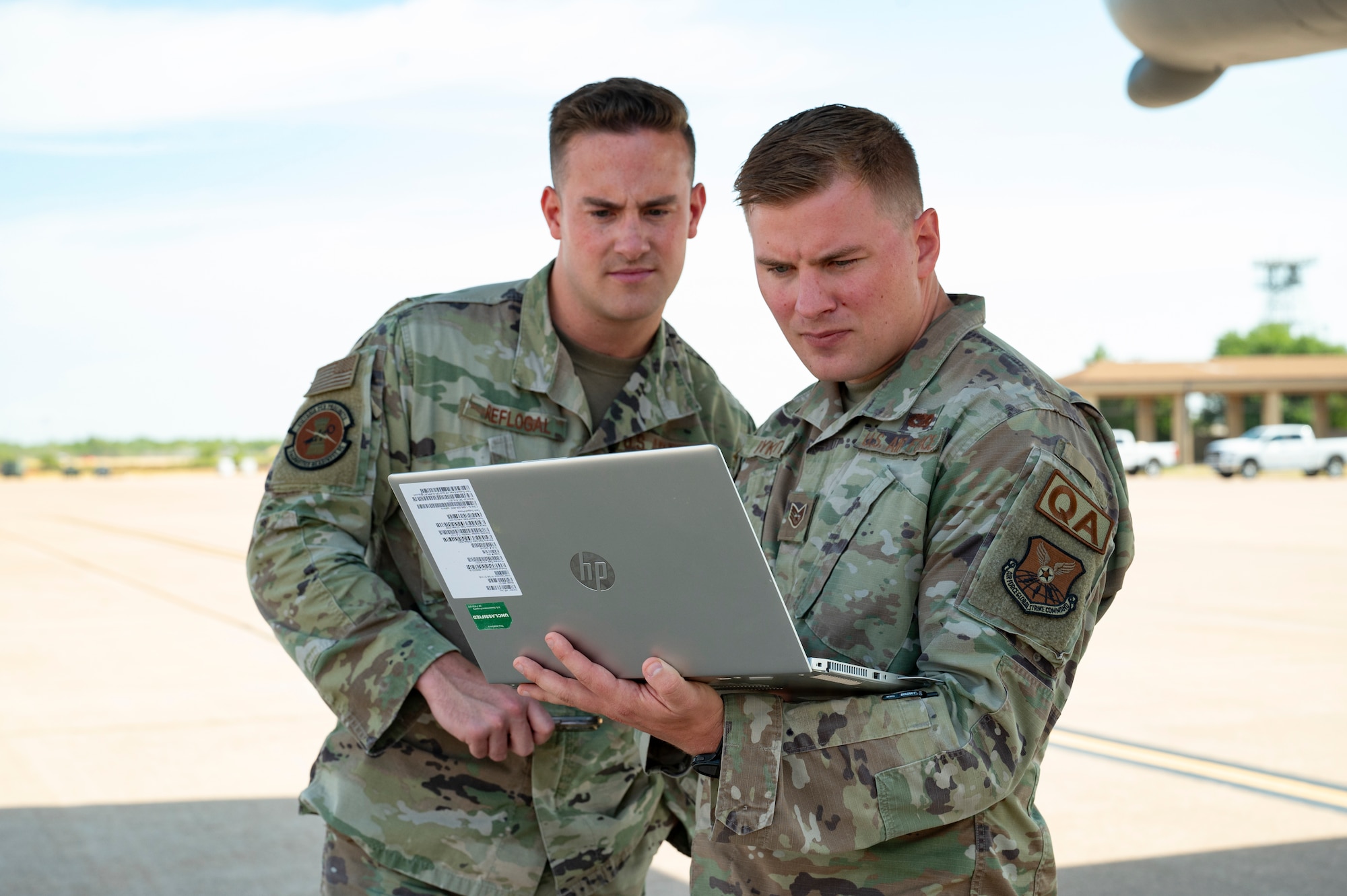 airmen look at a laptop on the flightine