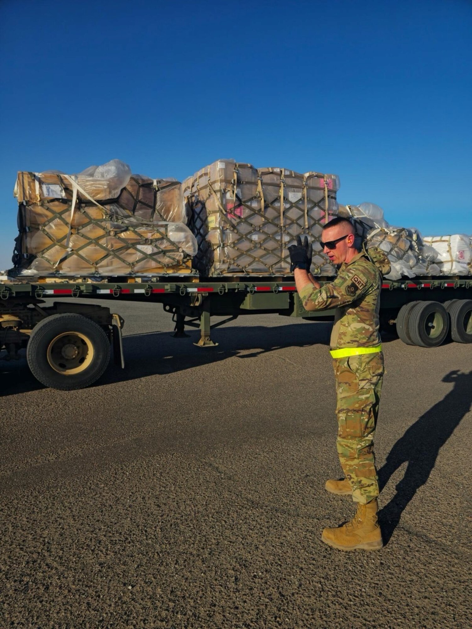 An aerial porter from the 387th Air Expeditionary Squadron’s Quick Reaction Team guides a truck full of pallets.
