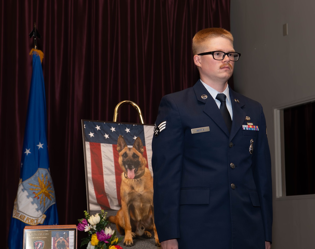 U.S. Air Force Senior Airman William Hepp V, 374th Security Forces Squadron military working dog handler, stands at attention to receive a certificate of Meritorious Service in honor of Tek.