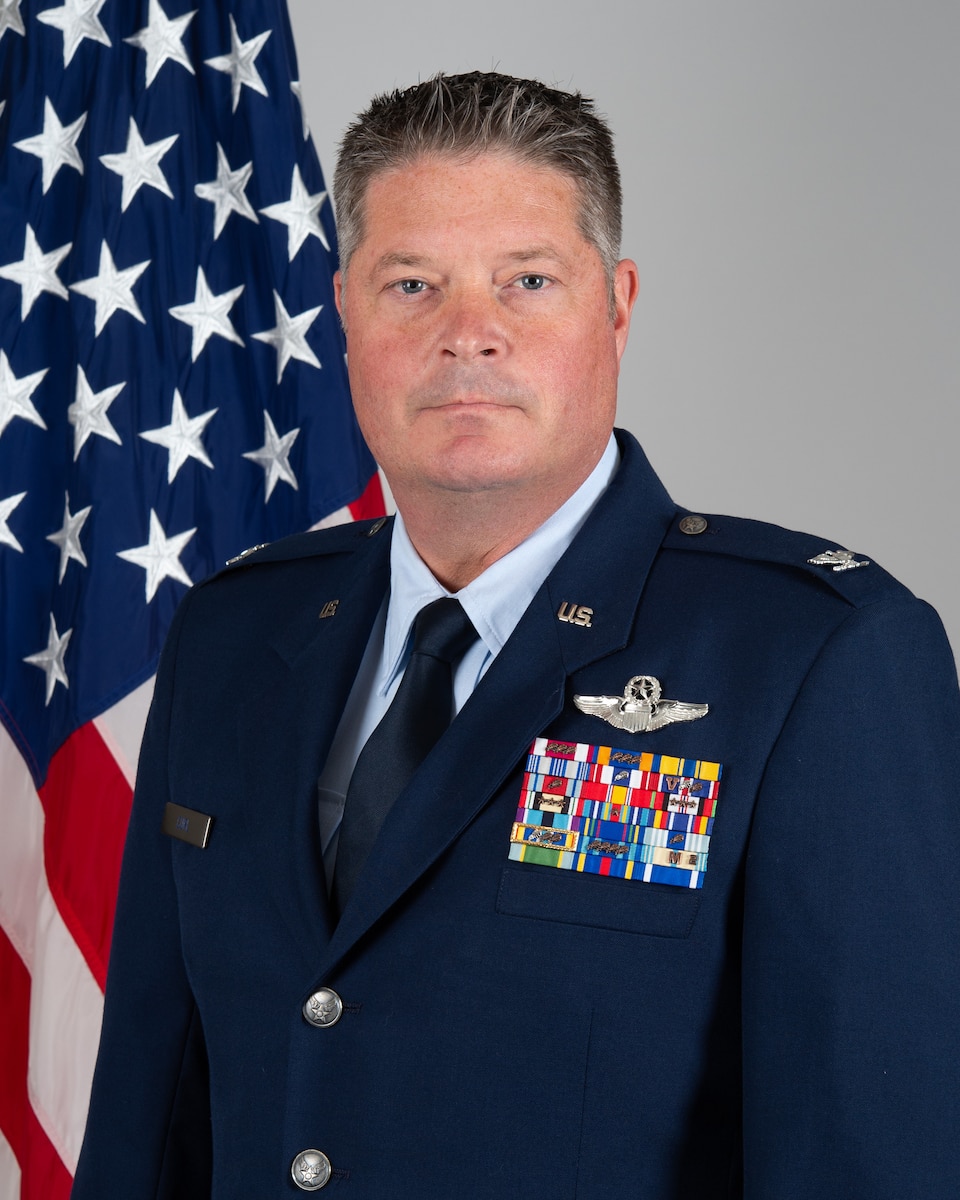 An official portrait of Col. David W. Curl, 434th Operations Group commander in a U.S. Air Force dress uniform. Behind one of his shoulders, an American flag.