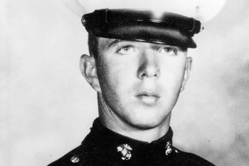 A person in uniform and cap poses for a black and white photo.