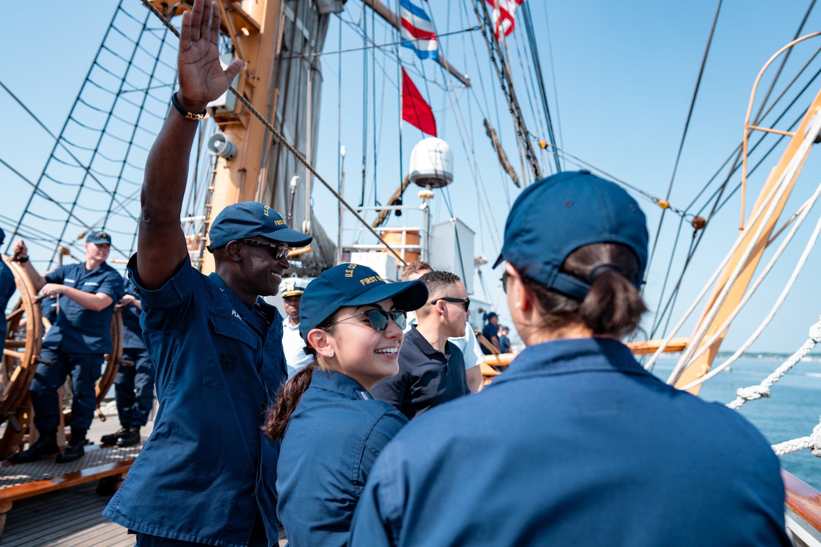 U.S. Coast Guard Rear Adm. Michael Platt, the commander of the Coast Guard’s First District, left, waves to Coast Guard members alongside Lt. j.g. Melanie Arroyave, command aid, aboard Coast Guard Cutter Eagle (WIX 327) during the cutter’s transit into Rockland, Maine, Aug. 2, 2024. Eagle, the Coast Guard’s First District and Station Rockland celebrated Rockland recertifying as an official Coast Guard City. (U.S. Coast Guard photo by Petty Officer 3rd Class Matt Thieme)