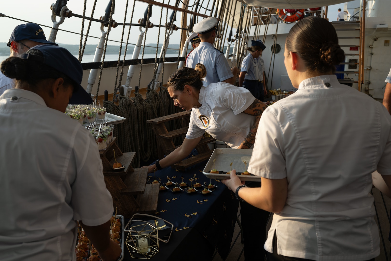 U.S. Coast Guard Senior Chief Petty Officer Nichol Billow, command chief and food service officer for Coast Guard Cutter Eagle (WIX 327), places appetizers on a prepared table aboard the ship during a reception to celebrate Rockland, Maine, as a Coast Guard City, Aug. 2, 2024. Eagle’s command, crew and Coast Guard Academy cadets hosted the reception while the ship was anchored in Rockland Harbor.