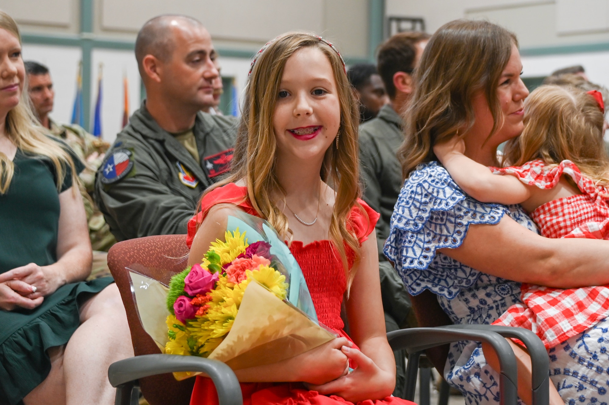 Haley Blackburn, daughter of a 301st Fighter Wing pilot, smiles while holding flowers that she received during the 301st Operations Group assumption of command ceremony Aug. 3, 2024 at Naval Air Station Joint Reserve Base Fort Worth, Texas. Blackburn sang the national anthem to start the ceremony. (U.S. Air Force photo by Staff Sgt. Celeste Zuniga)