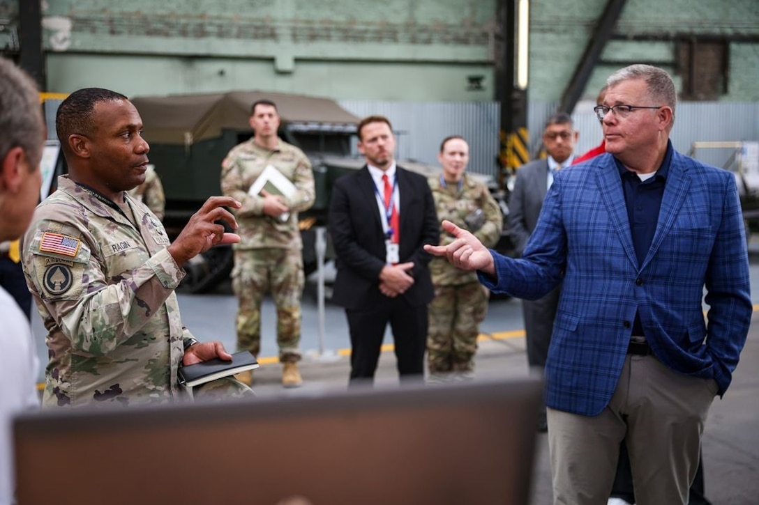 Two men talk with a group of people in the background