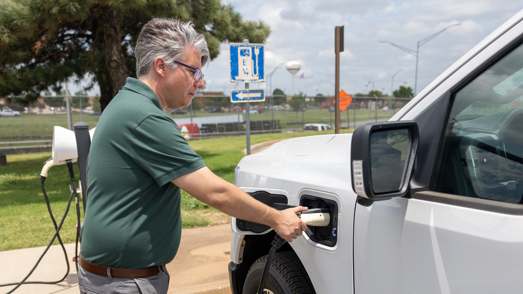 man plugs electric truck in