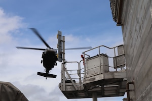 A photo of a helicopter over a ship.