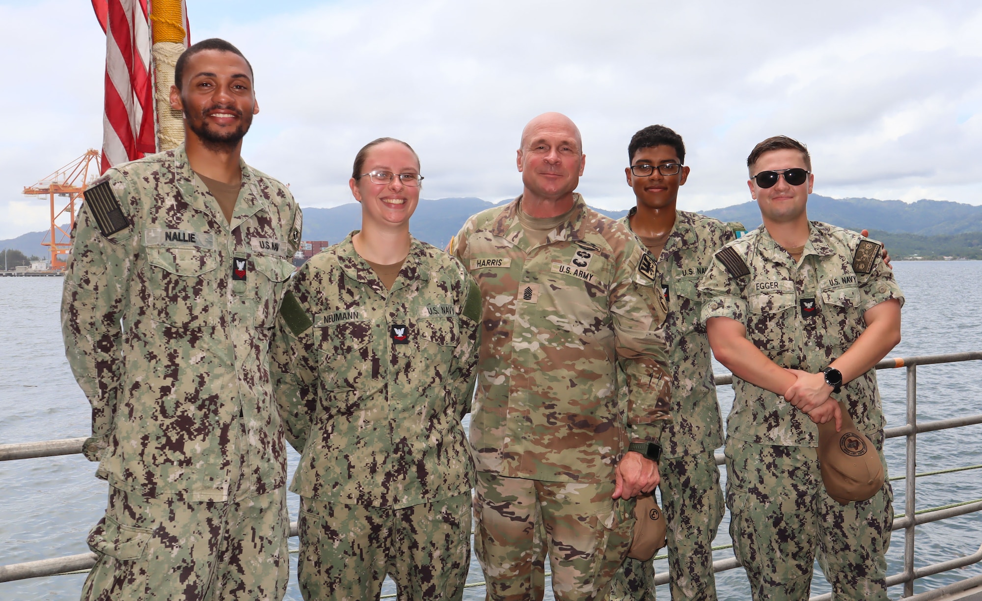 A photo of Sailors with a Soldier smiling.
