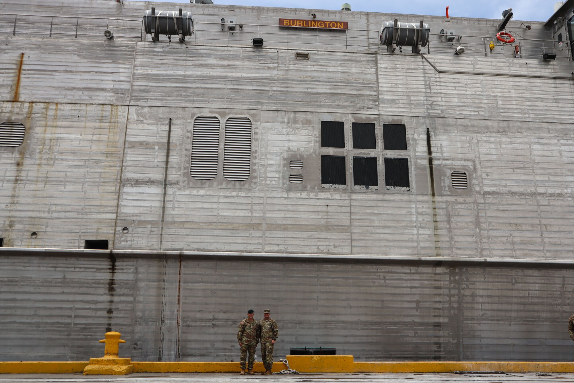 A photo of two Soldiers in front of a ship.