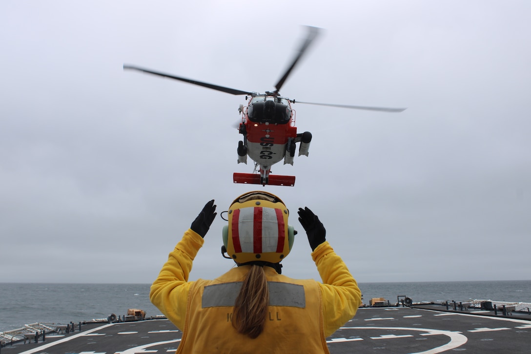 Ensign Matalynn Clark, a U.S. Coast Guard Cutter Kimball (WMSL 756) crew member, relays landing signals to an MH-60 Jayhawk helicopter aircrew from USCG Air Station Kodiak during a helicopter landing evolution while Kimball patrols the Bering Sea, May 11, 2024. During their patrol, Kimball also operated with a forward deployed MH-60 Jayhawk helicopter and aircrew in Cold Bay, Alaska, and the District Seventeen command center to execute complex SAR exercises for improving, coordination, response times, and range of rotary Coast Guard assets to assist mariners in distress. U.S. Coast Guard photo by Ensign James Bongard.