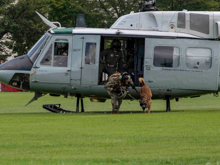 Staff Sgt. Patrick Grandison, 374th Security Forces Squadron military working dog handler, and his dog, Tek, exit a UH-1N Iroquois.