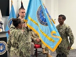 Three U.S. Navy officers engage in an establishment ceremony with the newly unfurled guidon.