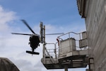 A photo of a helicopter over a ship.