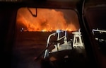 A photo of a fire out on the water from the perspective of a rescue boat.