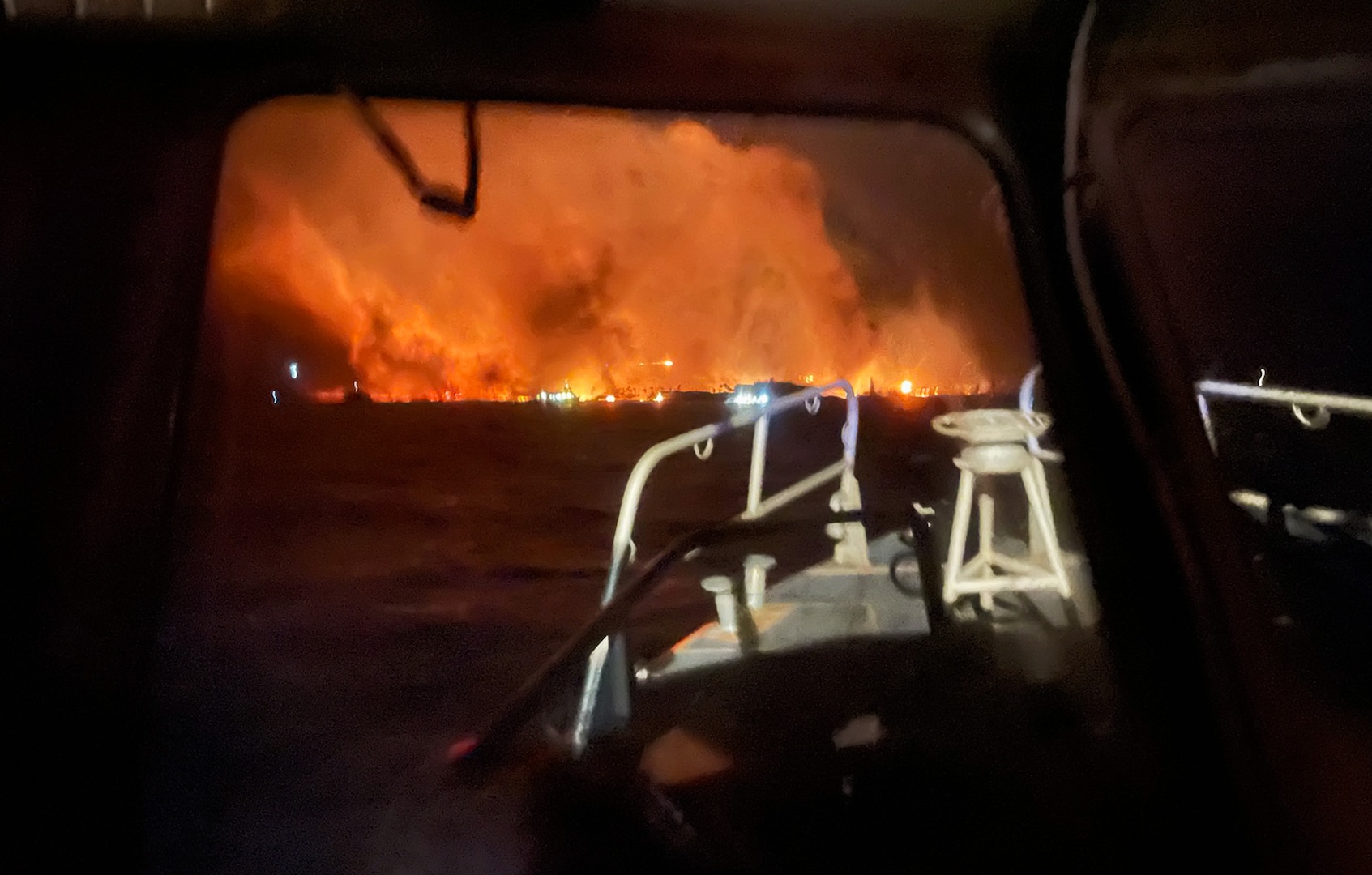 A photo of a fire out on the water from the perspective of a rescue boat.