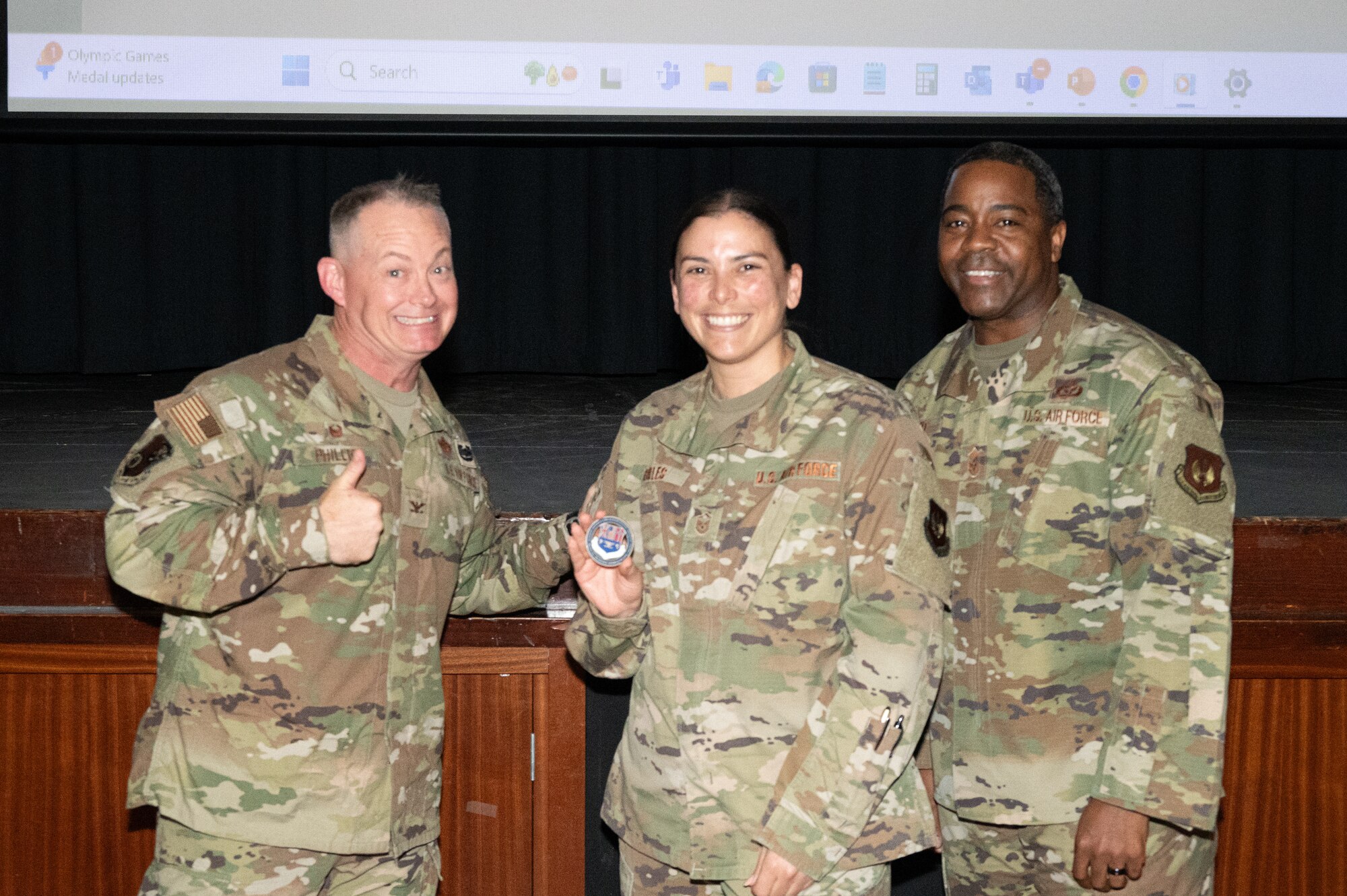 U.S. Air Force Col. D. Landon Phillips, 501st Combat Support Wing commander, left, and Chief Master Sgt. Terrance Boyd, 501st Combat Support Wing command chief, right, presents a coin to Master Sgt. Tania Robles, 422nd Medical Squadron (MDS) public health non-commissioned officer in charge.