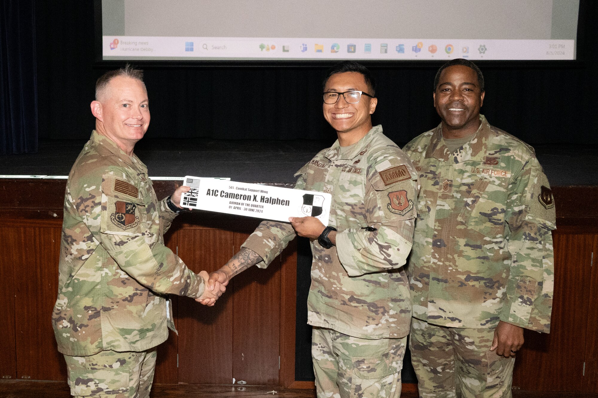 U.S. Air Force Col. D. Landon Phillips, 501st Combat Support Wing commander, left, and Chief Master Sgt. Terrance Boyd, 501st Combat Support Wing command chief, right, presents Tech. Sgt. A.J. Mangoba, 420th Munitions Squadron stockpile management section chief, with an Airman of the quarter award on behalf of Airman 1st Class Cameron Halphen, 420th Munitions Squadron conventional maintenance technician.