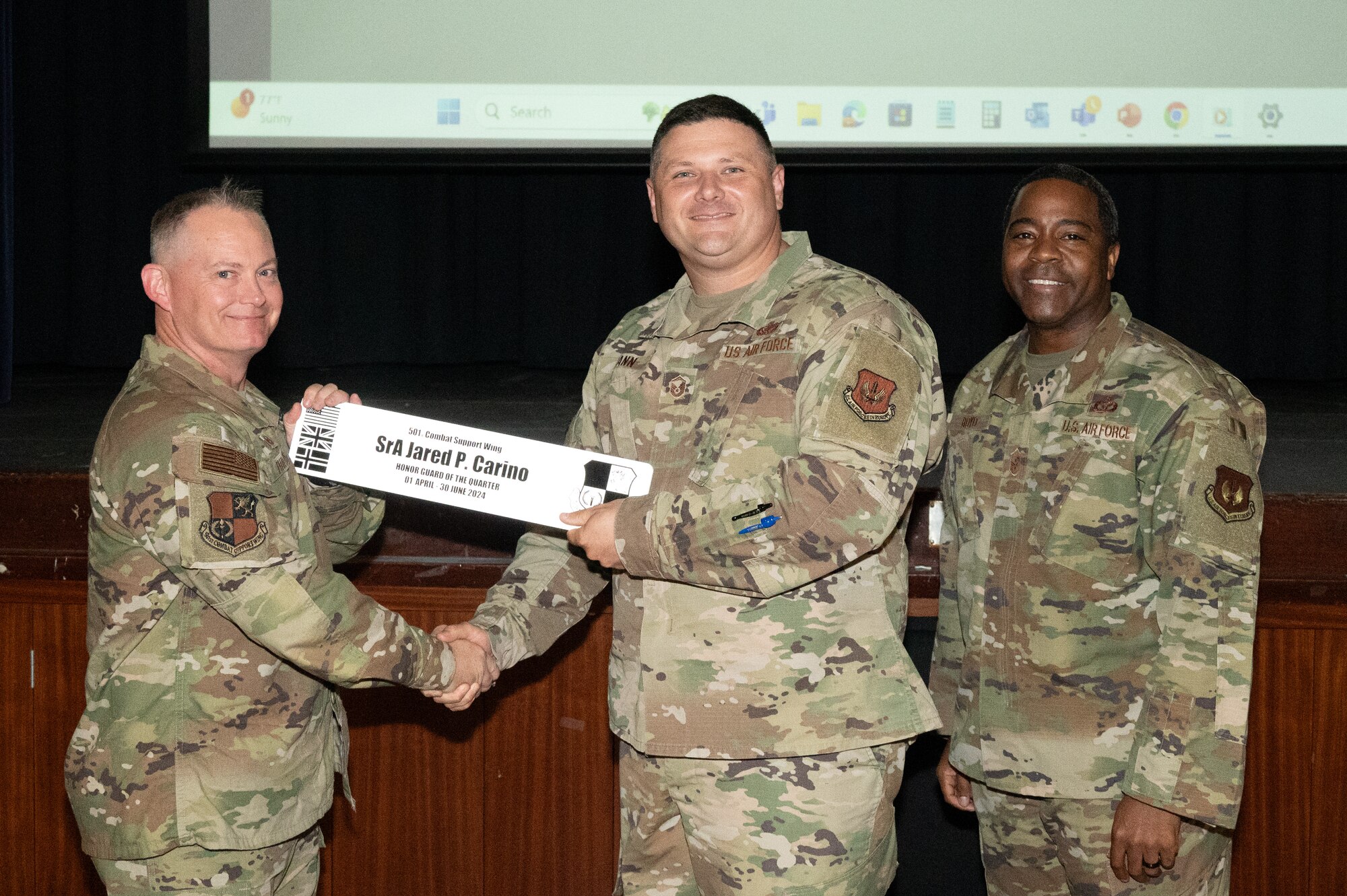 U.S. Air Force Col. D. Landon Phillips, 501st Combat Support Wing commander, left, and Chief Master Sgt. Terrance Boyd, 501st Combat Support Wing command chief, right, present Master Sgt. Theron Hann, 422nd Air Base Squadron senior enlisted leader, with a honor guard of the quarter award on behalf of Senior Airman Jared P. Carino, 422nd Communications Squadron satellite systems technician.