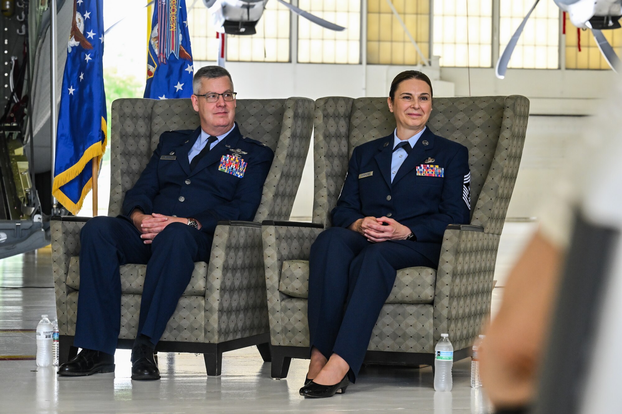 Col. Michael Maloney, 910th Airlift Wing commander, and Chief Master Sgt. Jennifer McKendree, 910th AW command chief, listen to remarks during McKendree's retirement ceremony at Youngstown Air Reserve Station, Ohio, Aug. 3, 2024.