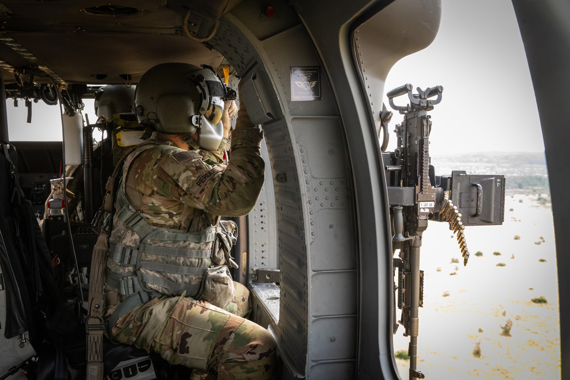 U.S. Army Sgt. Noah Perdue scans the impact area for targets in a UH-60 Blackhawk at Camp Grayling Army Airfield in Grayling, Michigan on July 16, 2024. Perdue is a Soldier in Bravo Company 2/147th Assault Helicopter Battalion, 63rd Theater Aviation Brigade,  who was conducting aerial gunnery during their annual training. (U.S. Army National Guard photo by Sgt. 1st Class Andrew Dickson)