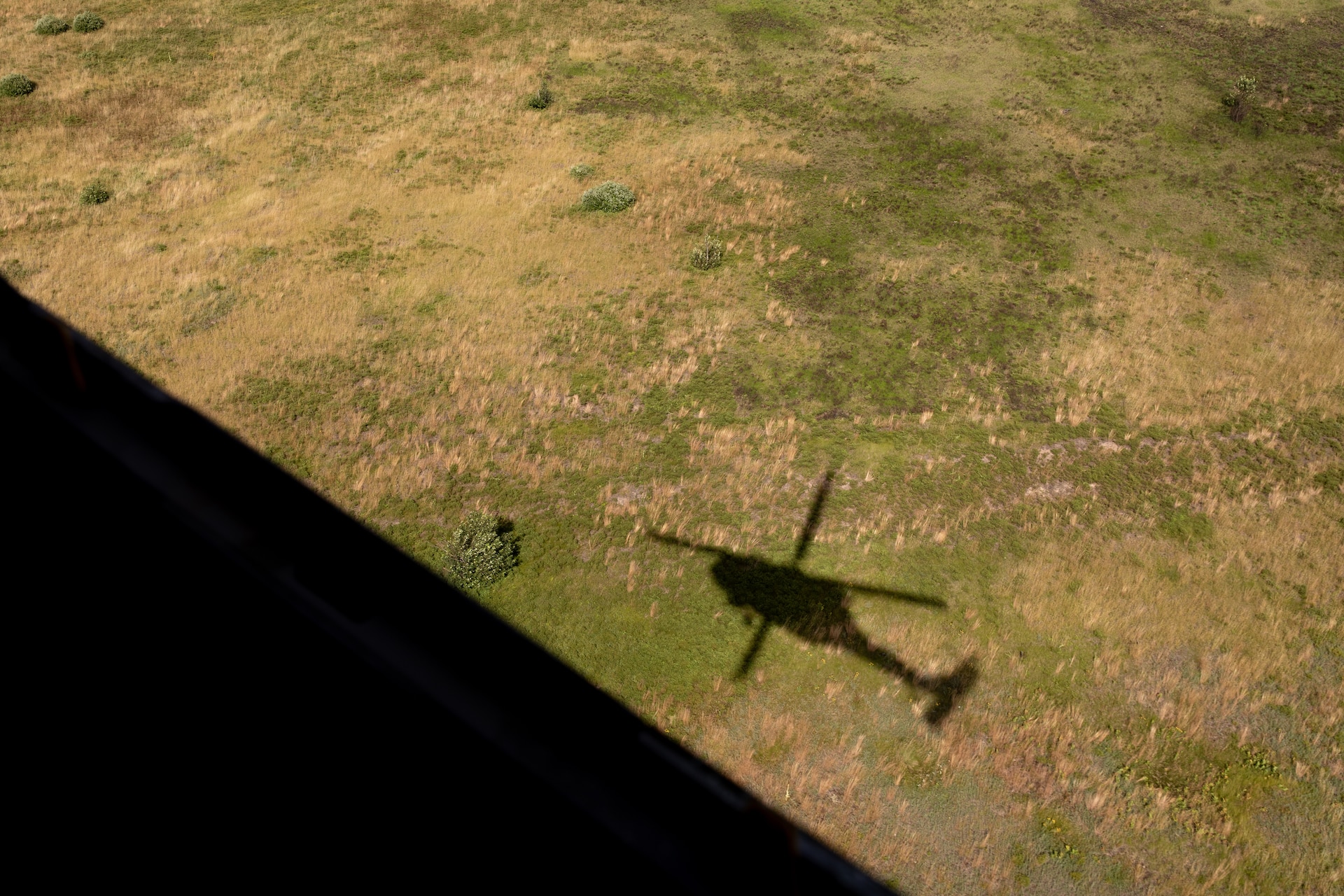 The shadow of a UH-60 Blackhawk helicopter over Camp Grayling Army Airfield in Grayling, Michigan on July 16, 2024. Soldiers of Bravo Company, 2/147th Assault Helicopter Battalion conducted aerial gunnery there as part of their annual training. (U.S. Army National Guard photo by Sgt. 1st Class Andrew Dickson)