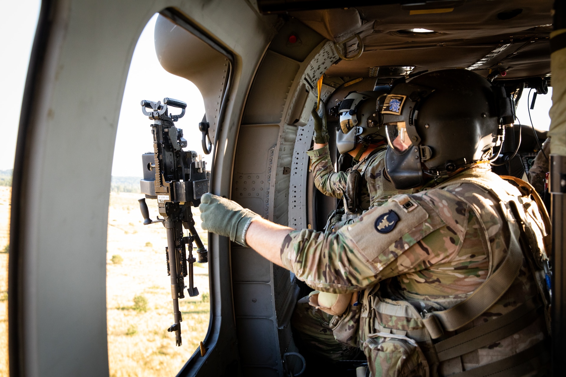 U.S. Army Spc. Austin Banks and Sgt. Michael Weegans scans for targerts during mounted gunnery in a UH-60 Blackhawk at Camp Grayling Army Airfield in Grayling, Michigan on July 16, 2024. Banks and Weegans are Soldiers in Bravo Company 2/147th Assault Helicopter Battalion, 63rd Theater Aviation Brigade,  who was conducting aerial gunnery during their annual training. (U.S. Army National Guard photo by Sgt. 1st Class Andrew Dickson)