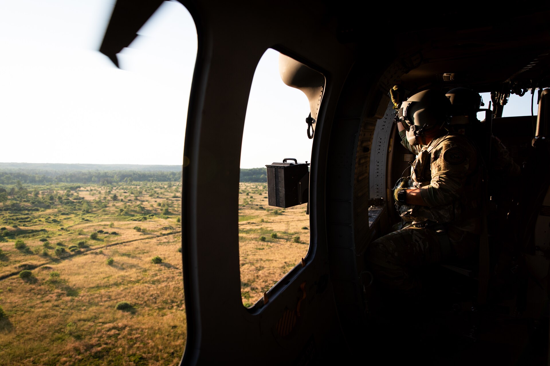 U.S. Army Spc. Austin Banks scans for targets during mounted gunnery in a UH-60 Blackhawk at Camp Grayling Army Airfield in Grayling, Michigan on July 16, 2024. Banks is a crew chief in Bravo Company 2/147th Assault Helicopter Battalion, 63rd Theater Aviation Brigade,  who was conducting aerial gunnery during their annual training. (U.S. Army National Guard photo by Sgt. 1st Class Andrew Dickson)