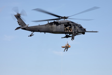 Alaska Air National Guard HH-60G Pave Hawk helicopter aviators assigned to the 210th Rescue Squadron hoist a 212th Rescue Squadron pararescueman and simulated casualty during a capabilities exercise over Malemute Drop Zone at Joint Base Elmendorf-Richardson, Alaska, June 25, 2024.