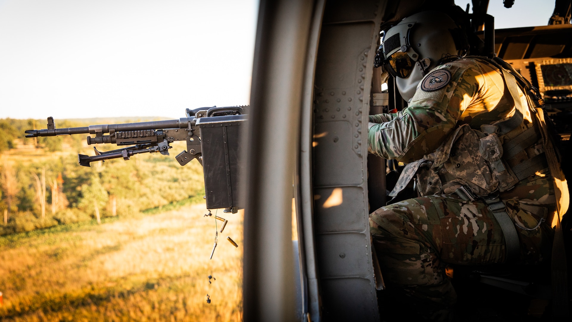 U.S. Army Spc. Austin Banks fires the M240 machine gun during mounted gunnery in a UH-60 Blackhawk at Camp Grayling Army Airfield in Grayling, Michigan on July 16, 2024. Banks is a crew chief in Bravo Company 2/147th Assault Helicopter Battalion, 63rd Theater Aviation Brigade,  who was conducting aerial gunnery during their annual training. (U.S. Army National Guard photo by Sgt. 1st Class Andrew Dickson)