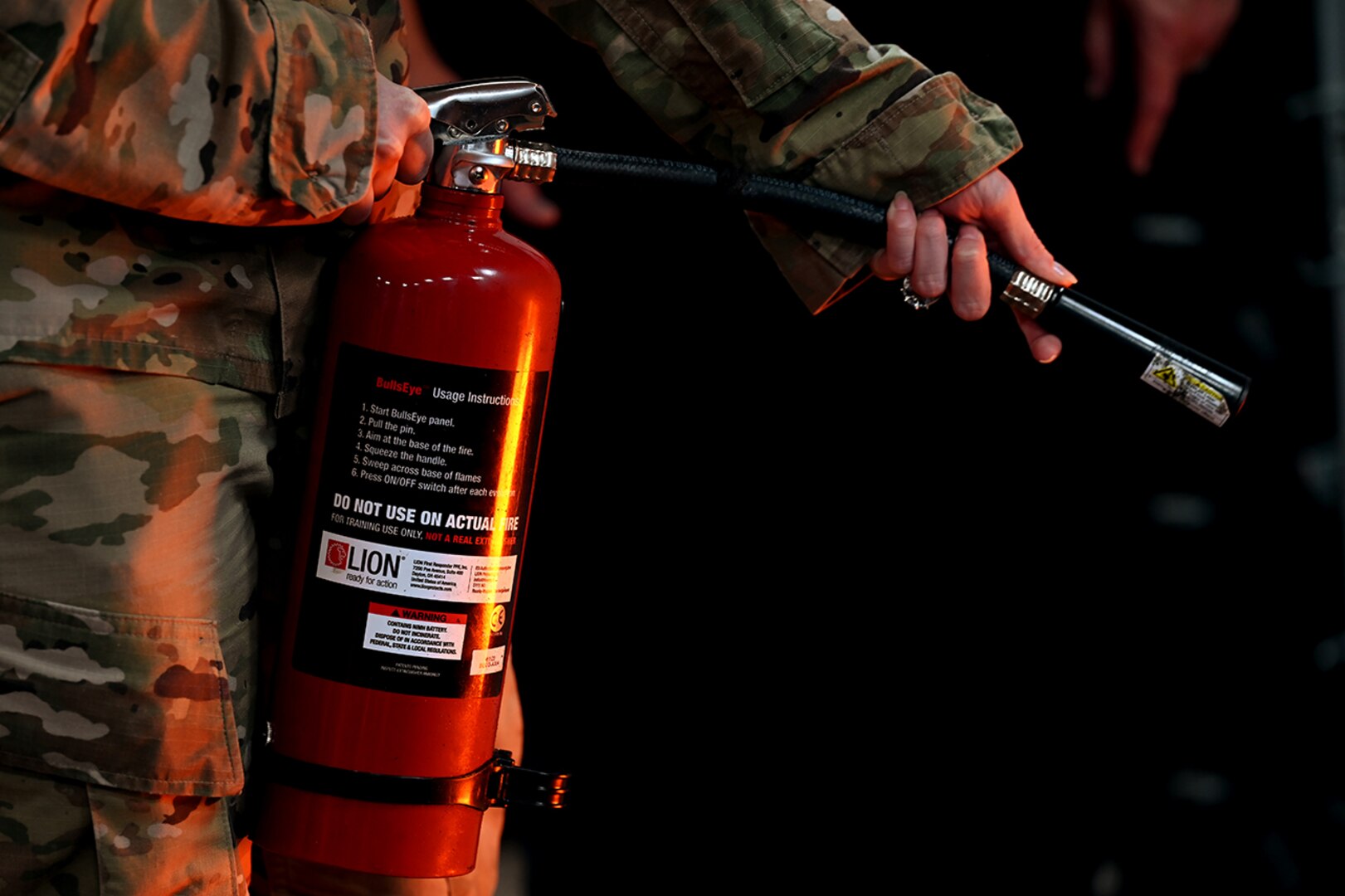 Airman holding a fire extinguisher pointing nozzle to the right.
